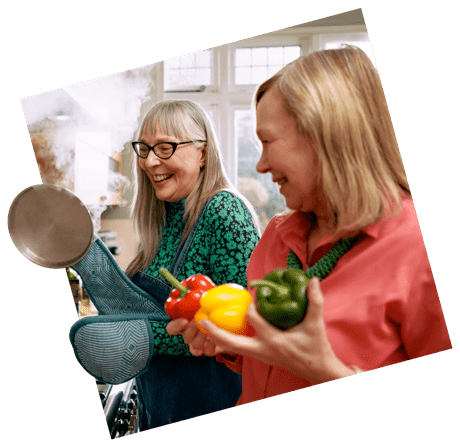 Two women smile cooking
