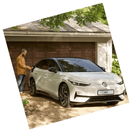 An OVI customer charging a white Volkswagen ID.7 electric vehicle parked in front of a garage