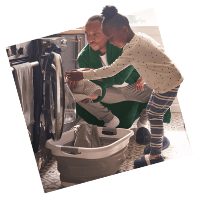 Man loading laundry with smiling partner stood behind