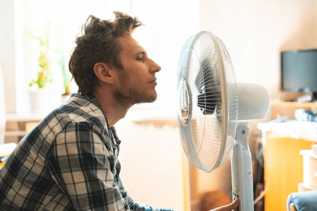 A man cools down with a fan on a hot day