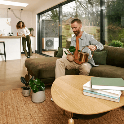 Man watering plant with heat pump in background