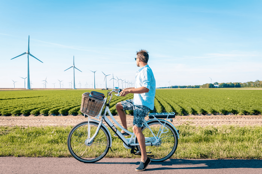 A man rides an e-bike alongside a wind farm