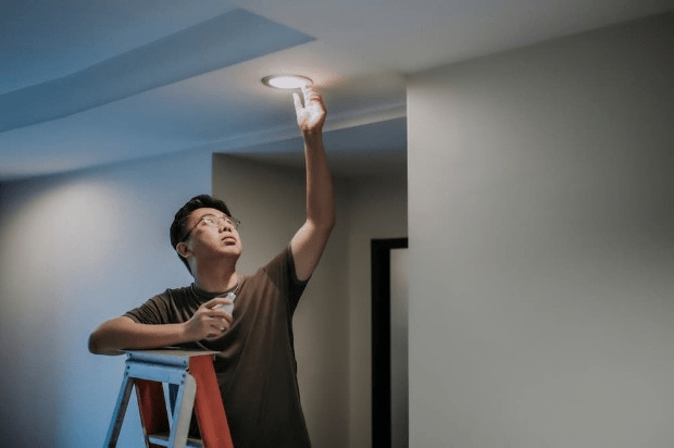 A man changing a smart light bulb at home