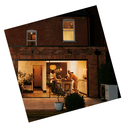 Family stood in cosy kitchen with heat pump in the garden