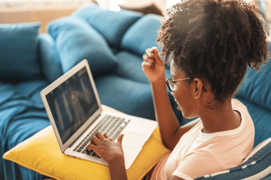 A woman with a laptop on a cushion. 