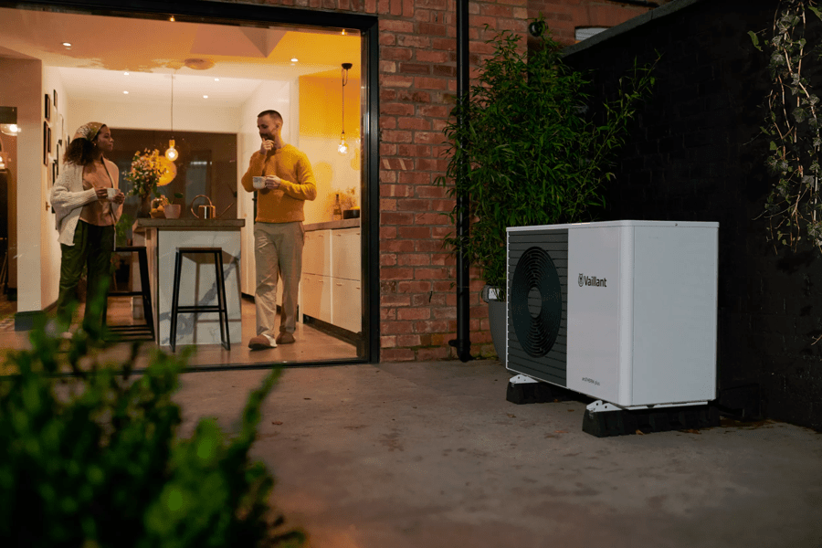 ir source heat pump in garden with couple stood outside house
