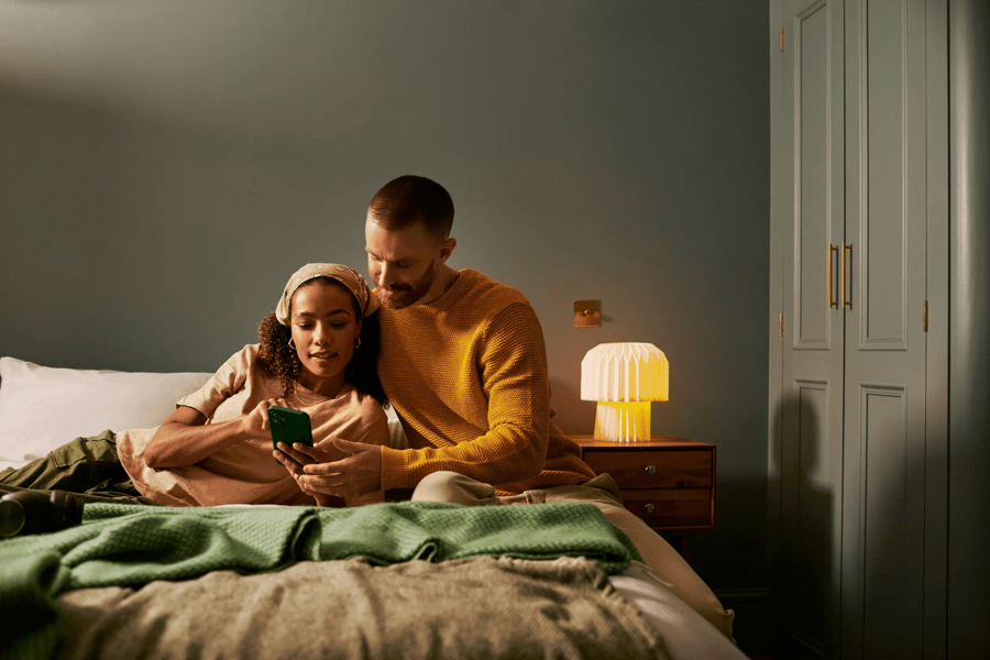 a couple sitting in bed looking at a phone