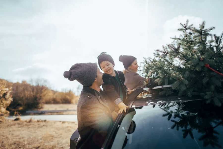 Dad and kids putting the Christmas tree on the car