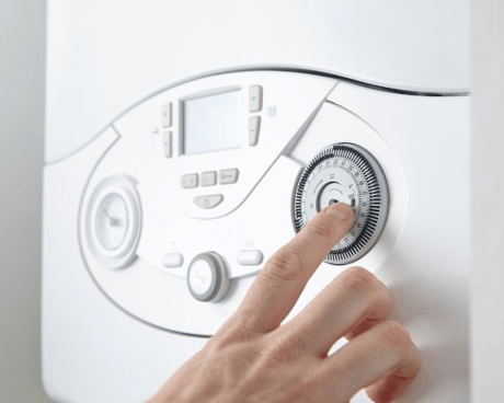 A finger moving a dial on a white boiler