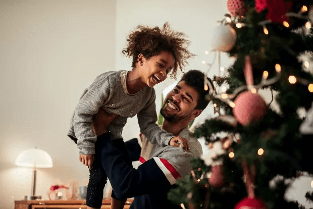 A man playing with a child by the Christmas tree