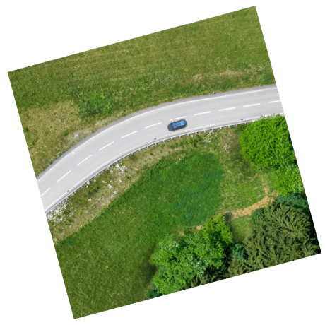 A bird's-eye view of a road with a car travelling on it