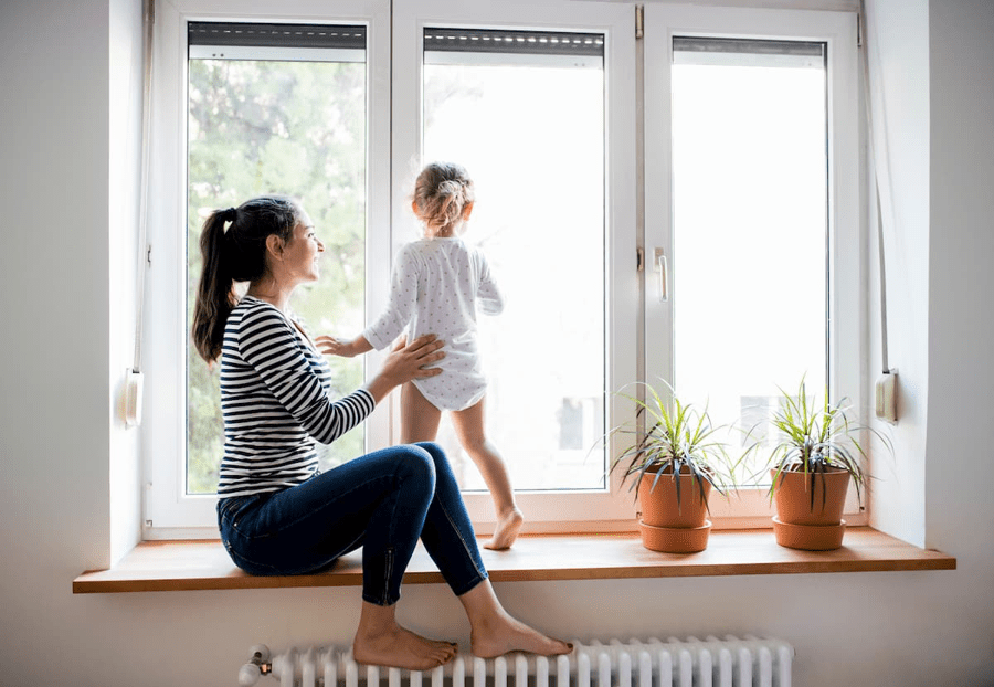 Mother supporting a young child looking out of a window