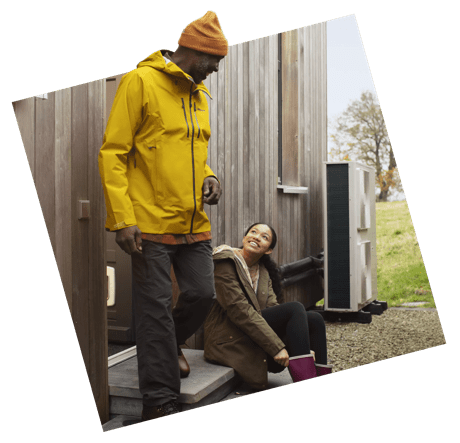 Father and daughter sat outside next to heat pump