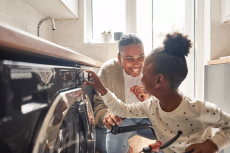 Mum and daughter putting the washing machine on