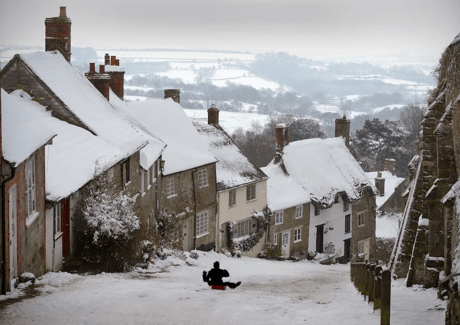 A middle-aged man sledges down a snow-covered road