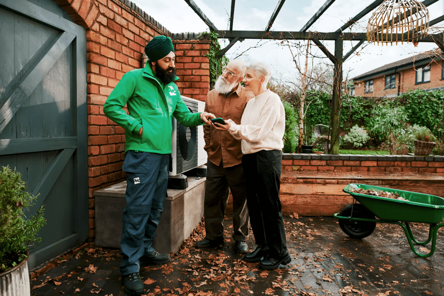 OVO engineer showing an older couple how to use their heat pump in the garden