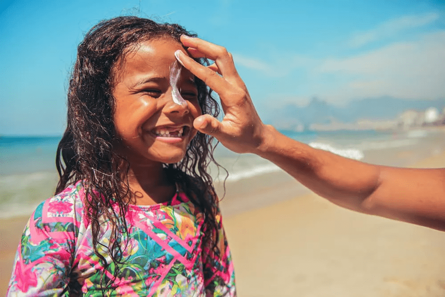 Girl applying sunscreen at the beach