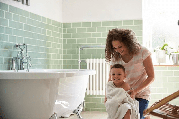 A woman wraps a child in a towel in the bathroom