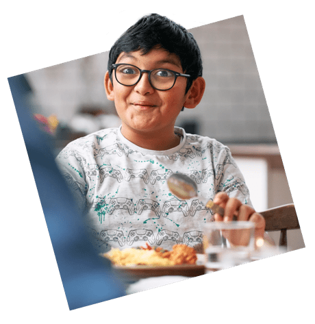 A boy enjoying a meal at a kitchen table