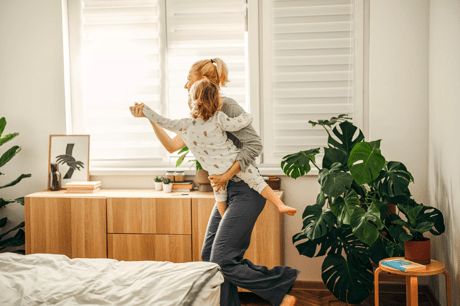 Mother holding her child and dancing around the bedroom