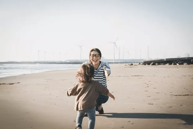 A family on the beach with wind turbines in the background
