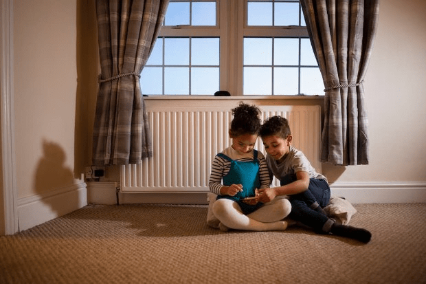 Children playing on the floor by a radiator