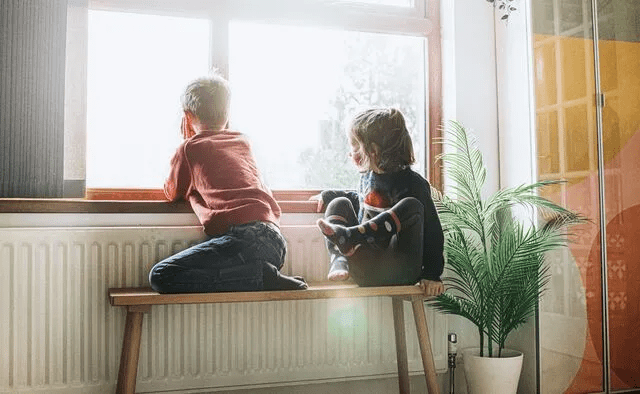 Children playing on the floor by a radiator