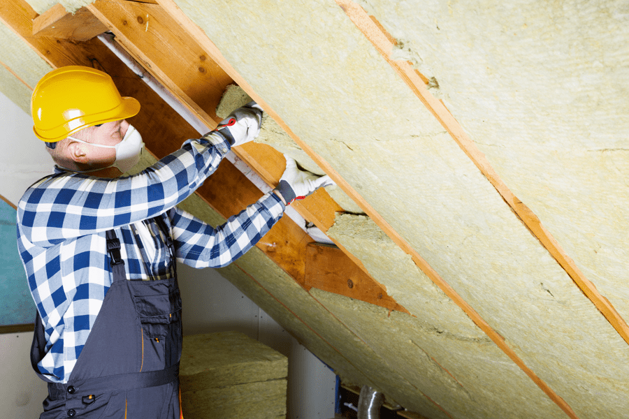 man insulating roof between rafters