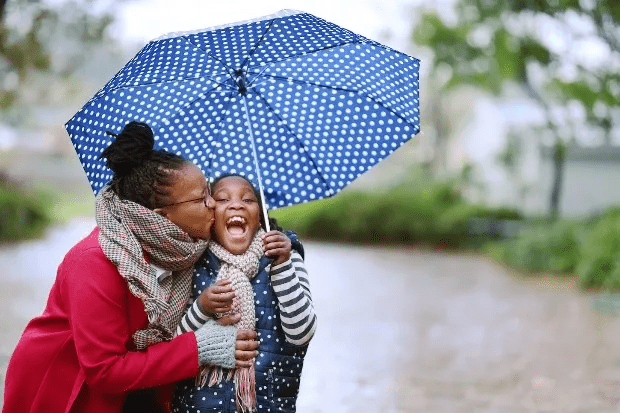 mum and daughter under umbrella in rain