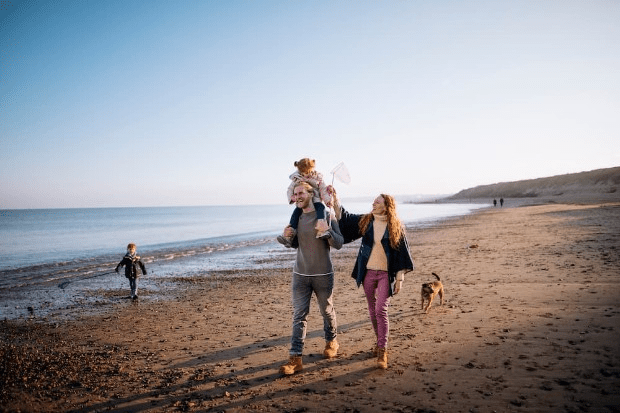 A family walking along the beach by the sea