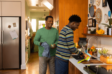 Two smiling men washing dishes