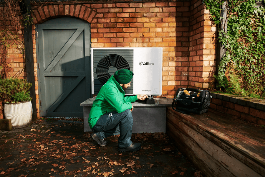 Man kneeling down fitting a heat pump in the garden