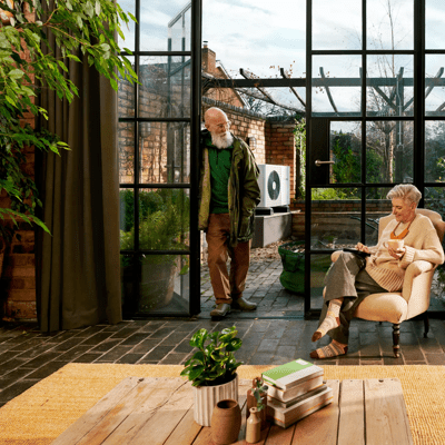 Couple sat inside with heat pump in background