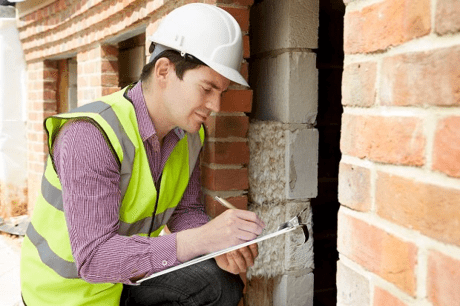 A workman with a clipboard carrying out a survey of a home