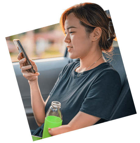 A woman sitting in a car, looking at a smart phone