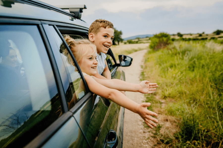 Kids look out of the family car