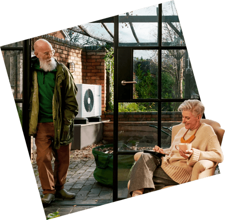 Couple sitting in the house with heat pump in background