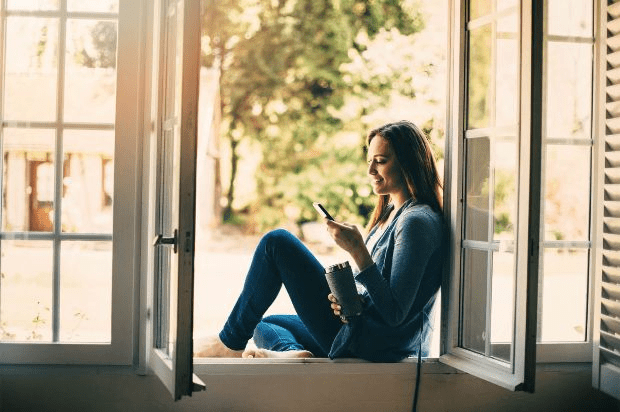 A woman sitting in the window using her smartphone