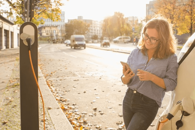 Woman charging electric car by the road