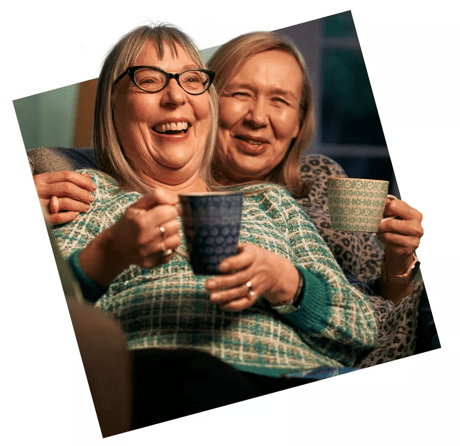 Two women laughing with cups of tea