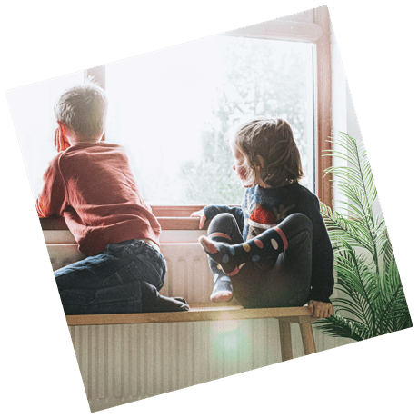 Two children sit looking out the window
